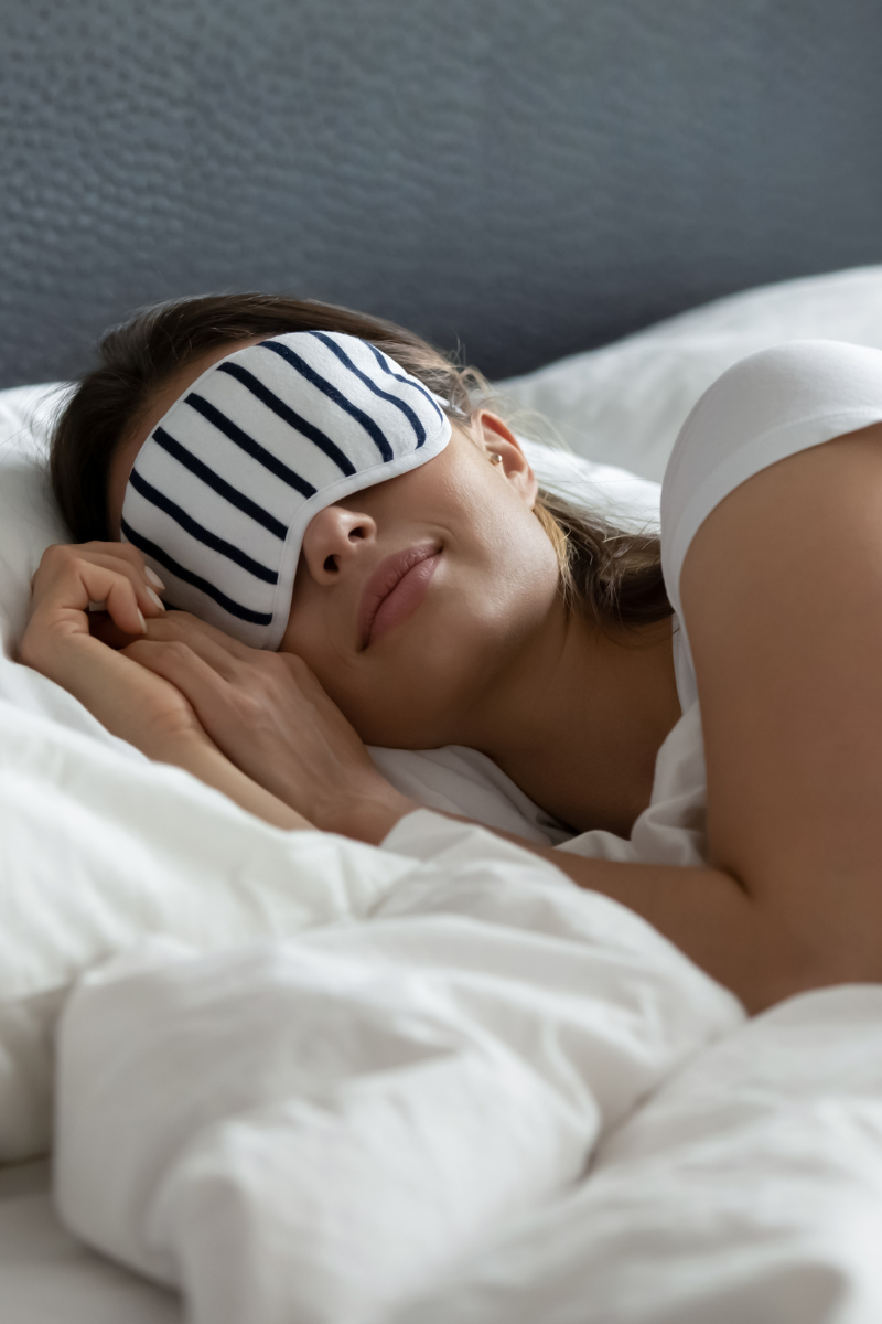 Person resting in bed while wearing an eye mask